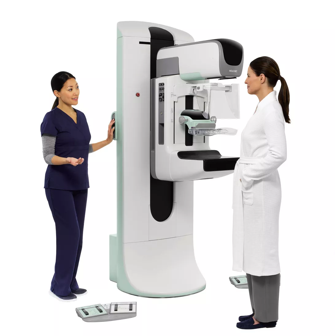 A radiographer and patient next to a Hologic 3Dimensions digital mammography system
